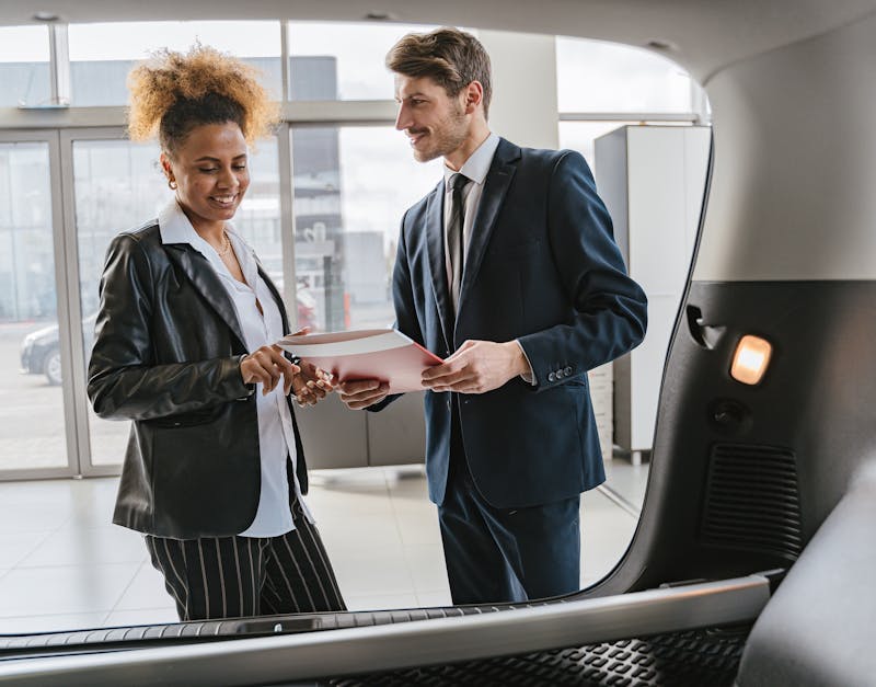 Dealer discussing vehicle options with a client inside a modern car showroom.